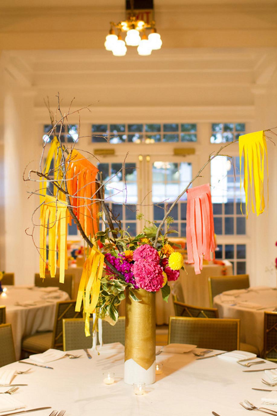 Tall, colorful floral wedding centerpiece with paper tassles