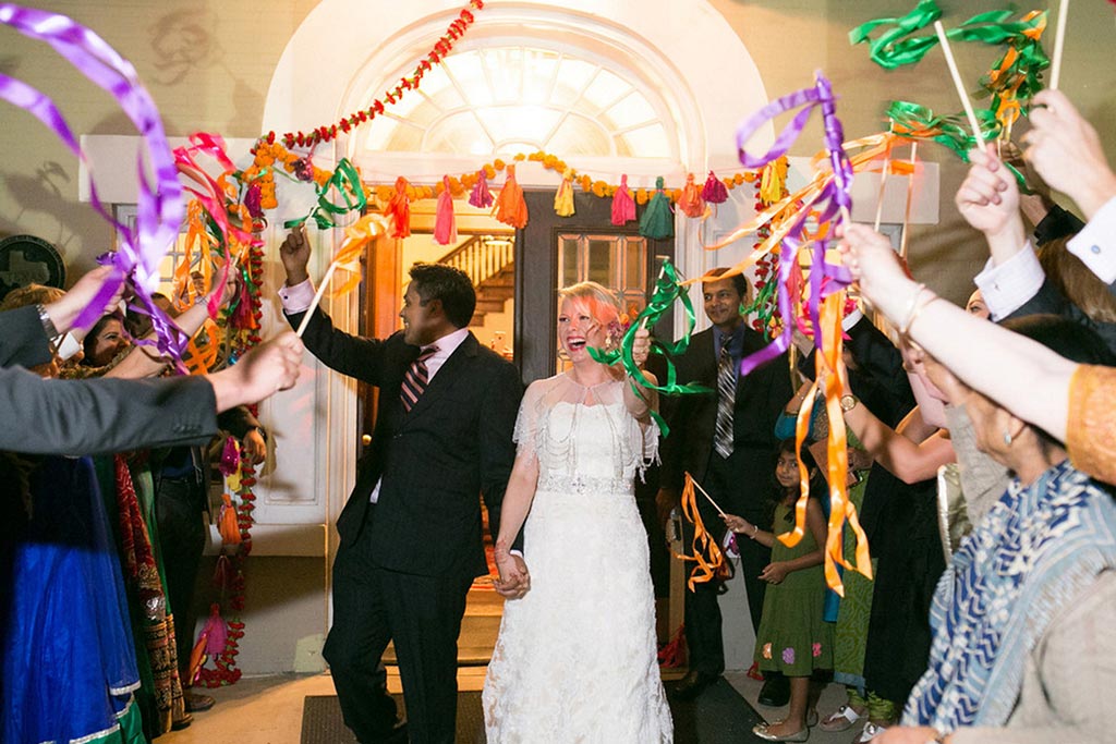 Bride and groom grand exit from wedding reception with colorful streamers at Belo Mansion in Dallas