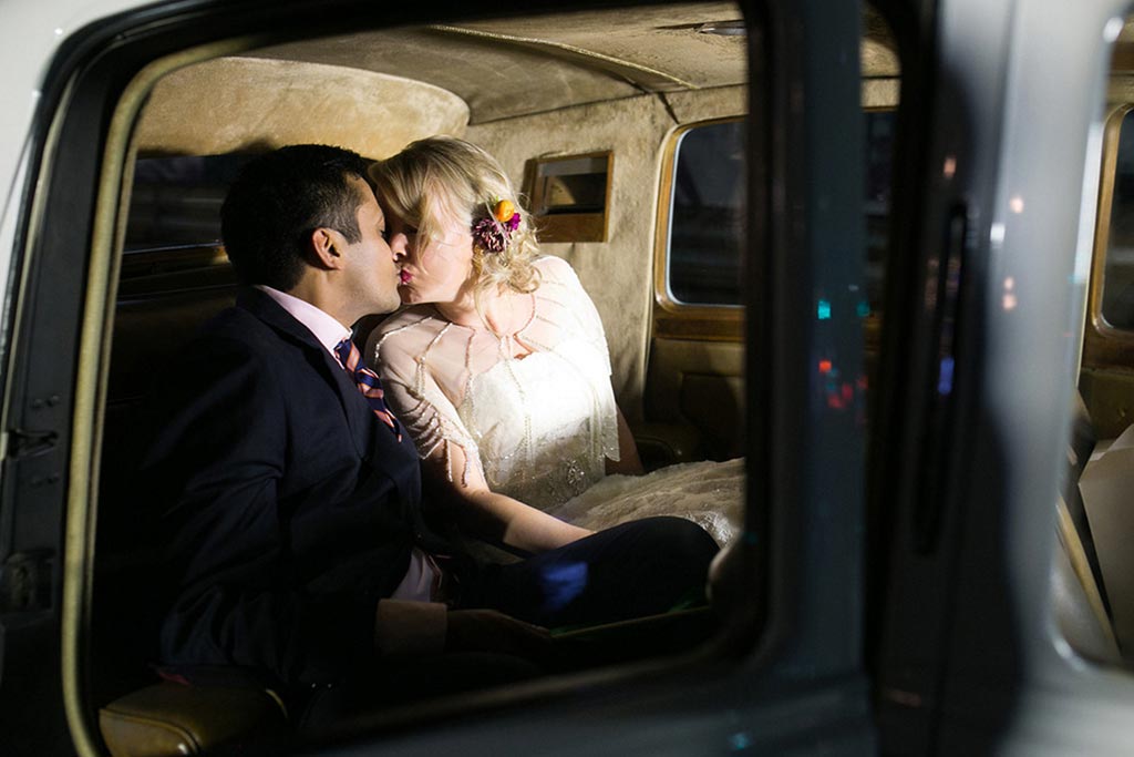 Bride and groom kiss in Rolls Royce after exit from wedding reception