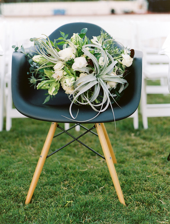 Bridal bouquet with an air plant on a black Eames dowel chair