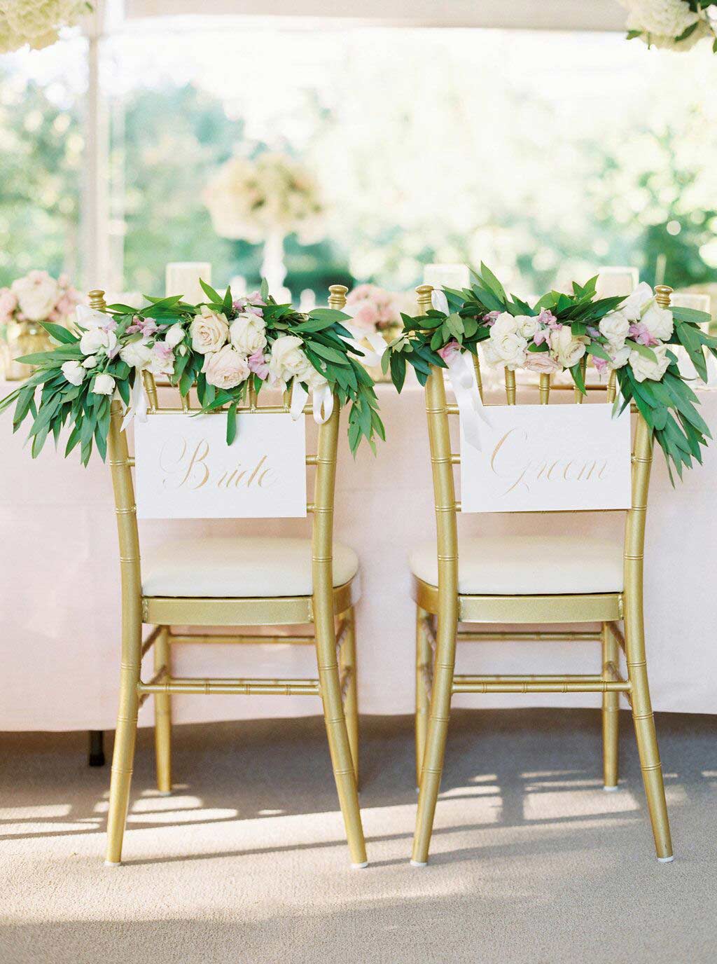 Greenery and blooms on gold chiavari bride and groom chairs