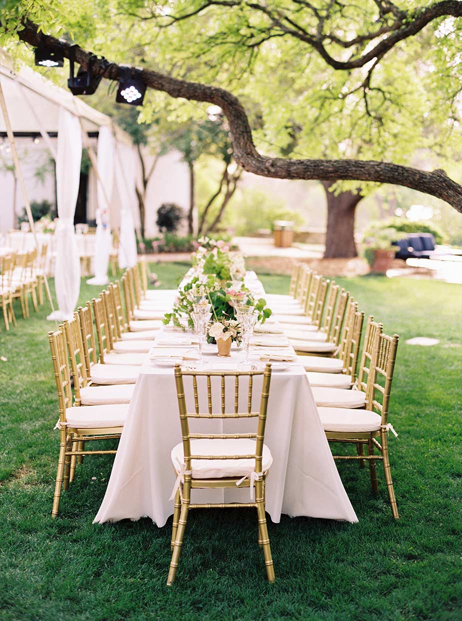 Long wedding reception table setup with gold chiavari chairs at The Degolyer House at The Dallas Arboretum