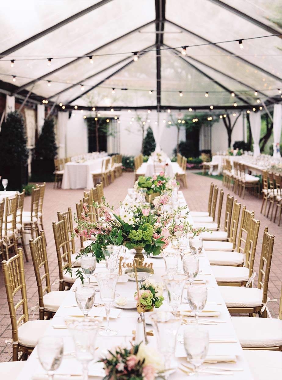 Long wedding reception table detail with cafe lighting and clear tent at The Degolyer House at The Dallas Arboretum