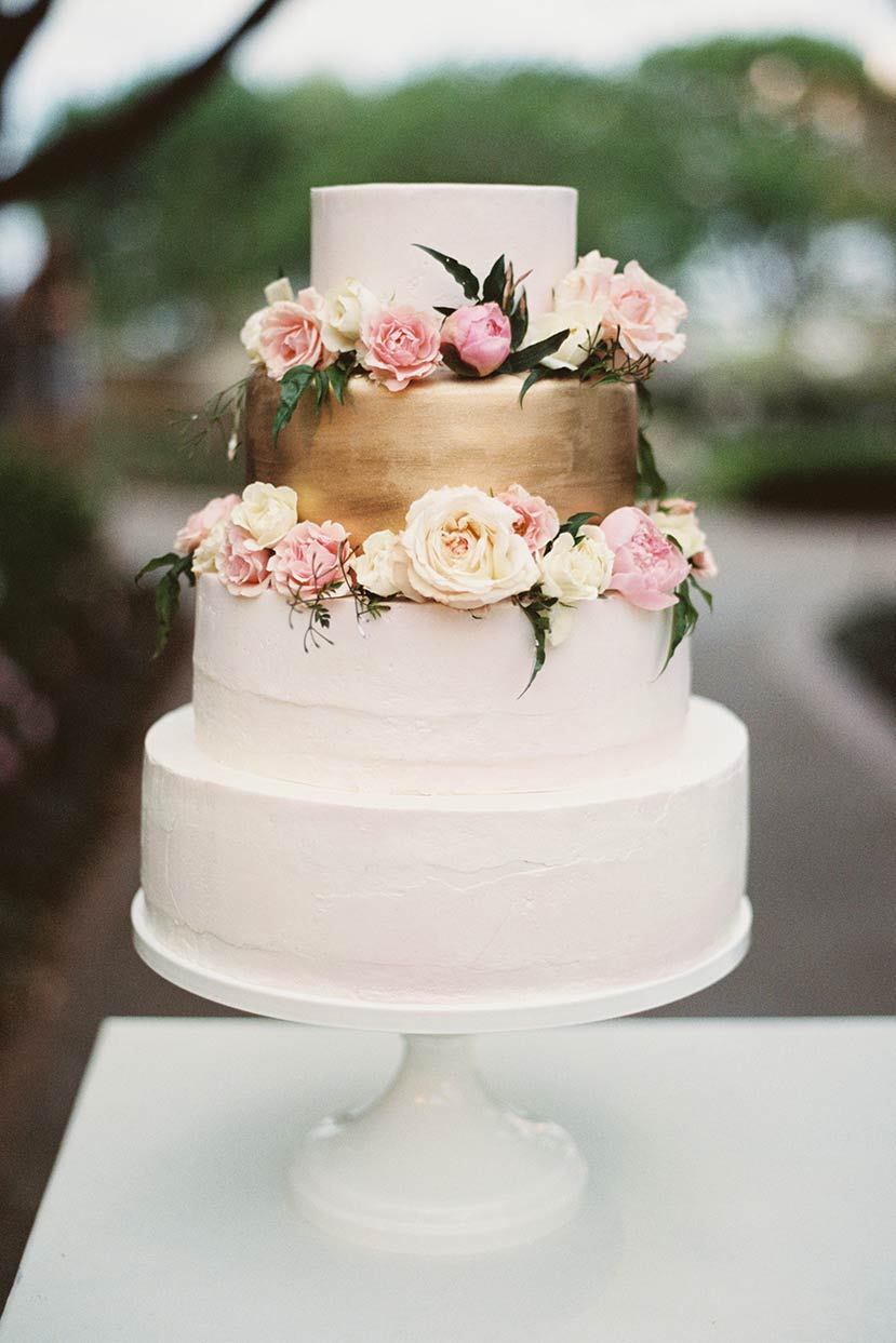 White and gold buttercream wedding bridal cake with fresh flowers