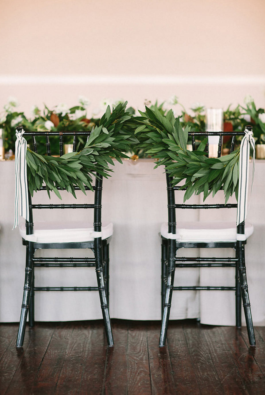 Bride and groom floral chair with swags of greenery and ribbon