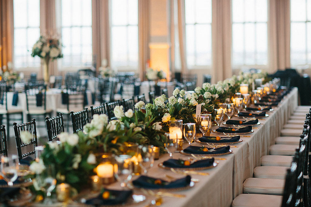 Long head table with floral garland and candles at wedding reception at The Room on Main in Dallas, Texas