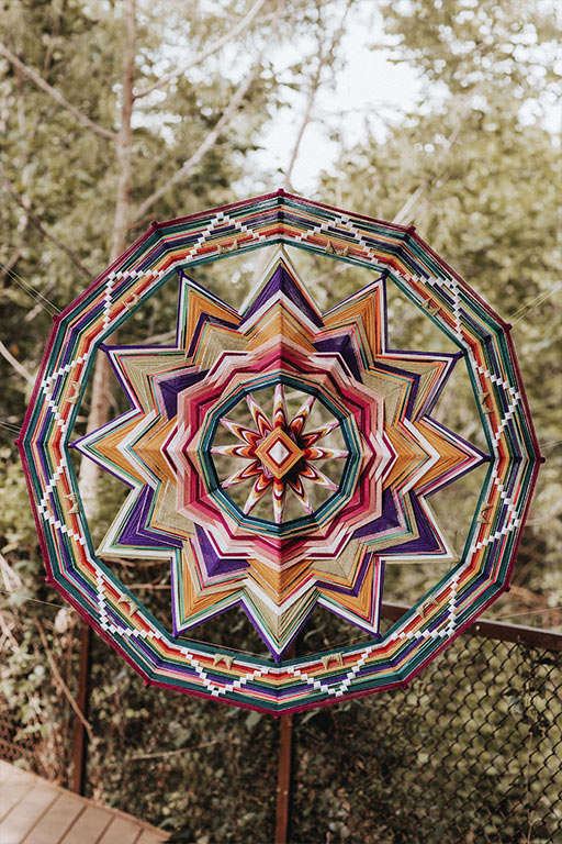 A colorful, giant ojo de Dios or eye of God, by Jay the Weaver, used as a wedding altar decoration