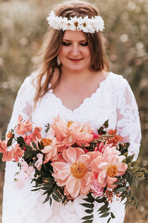 Wedding day bridal portrait with daisy chain headpiece, a bouquet with shades of pink and custom Patti Flowers wedding gown