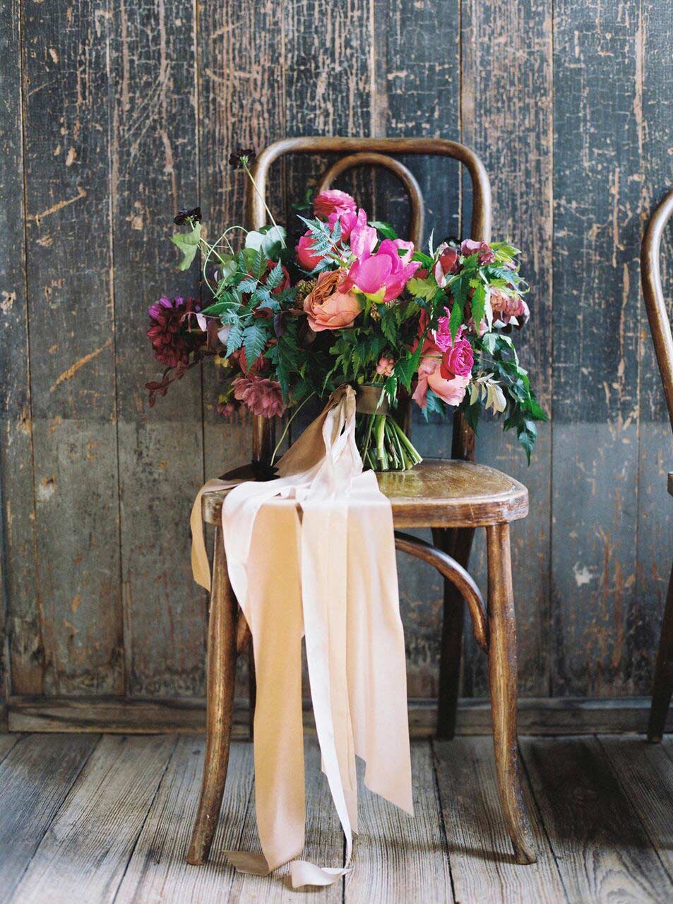 Bridal bouquet with long silk ribbon streamers on wooden chair