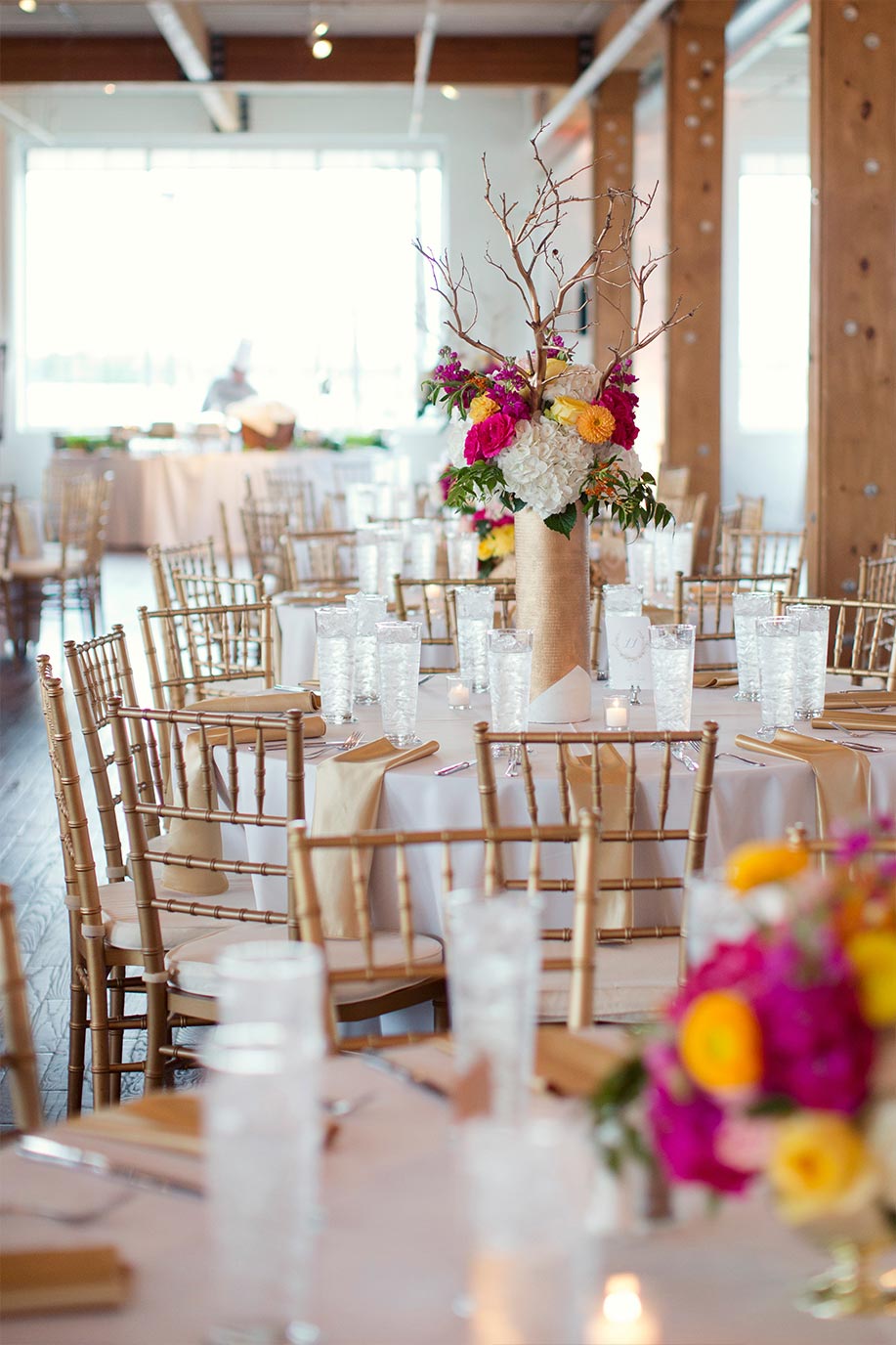 Wedding reception round tables with tall branch centerpiece and gold chiavari chairs