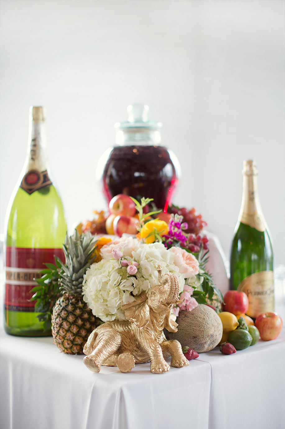 Sangria bar wedding setup with gold elephant statue and fruit