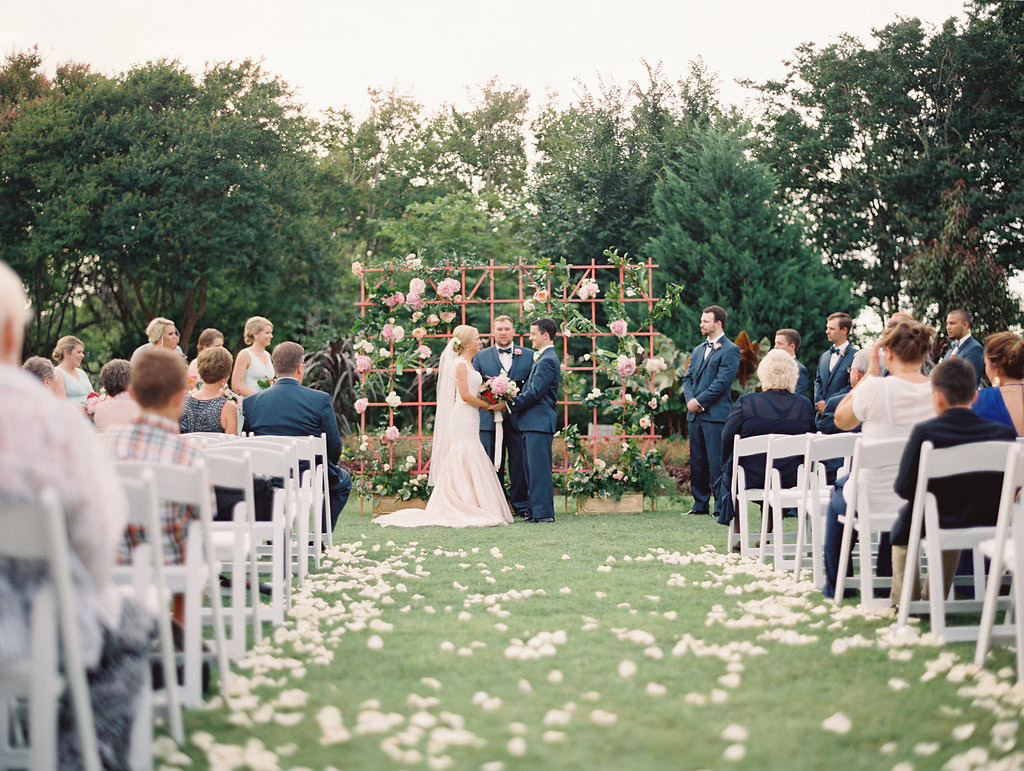 Bride and groom in front of floral lattice altar backdrop at wedding ceremony at The Dallas Arboretum