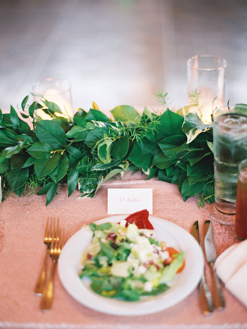 Green garland table runner and wedding place setting with salad