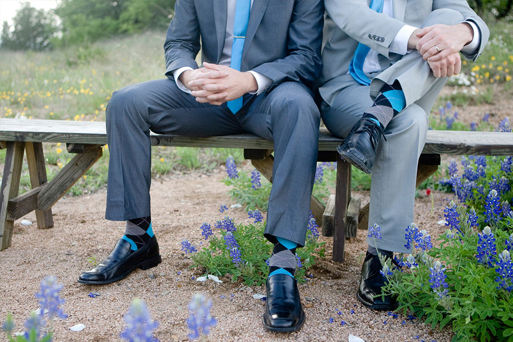 groom and groomsmen sitting on bench with Texas bluebonnets