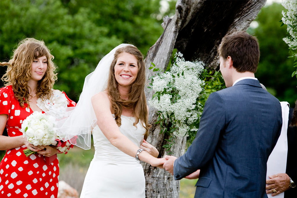 Texas Hill Country wedding ceremony with bridesmaid wearing red polka dot dress