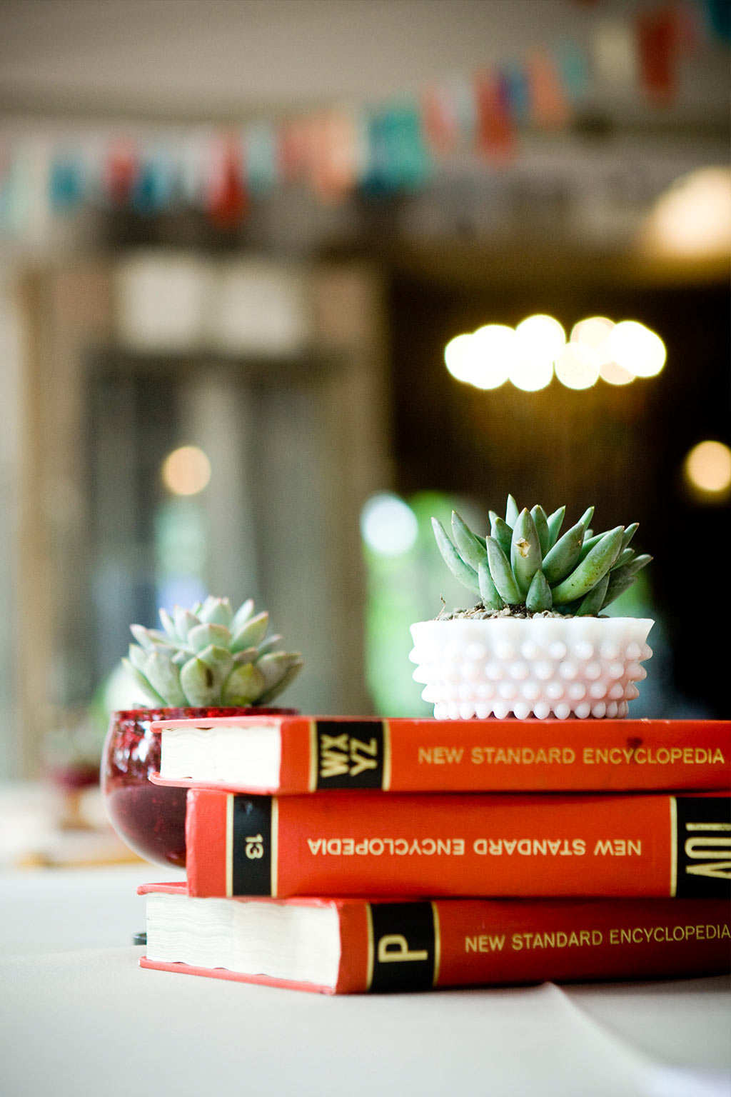 vintage encyclopedias, milk glass and succulents used for wedding reception table centerpiece