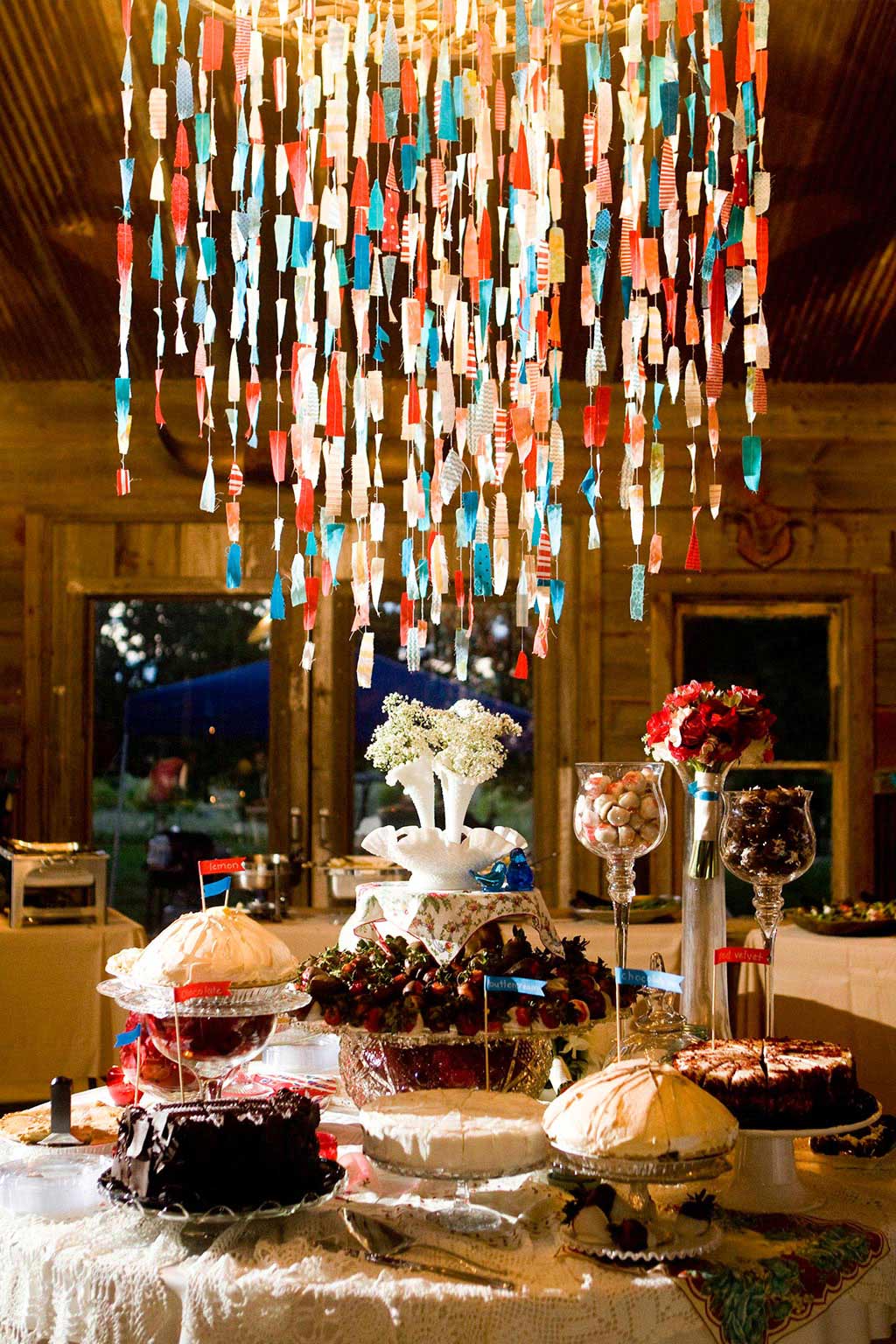 amazing dessert table with pies and cake with cloth streamers hanging on chandelier at Texas Hill Country wedding
