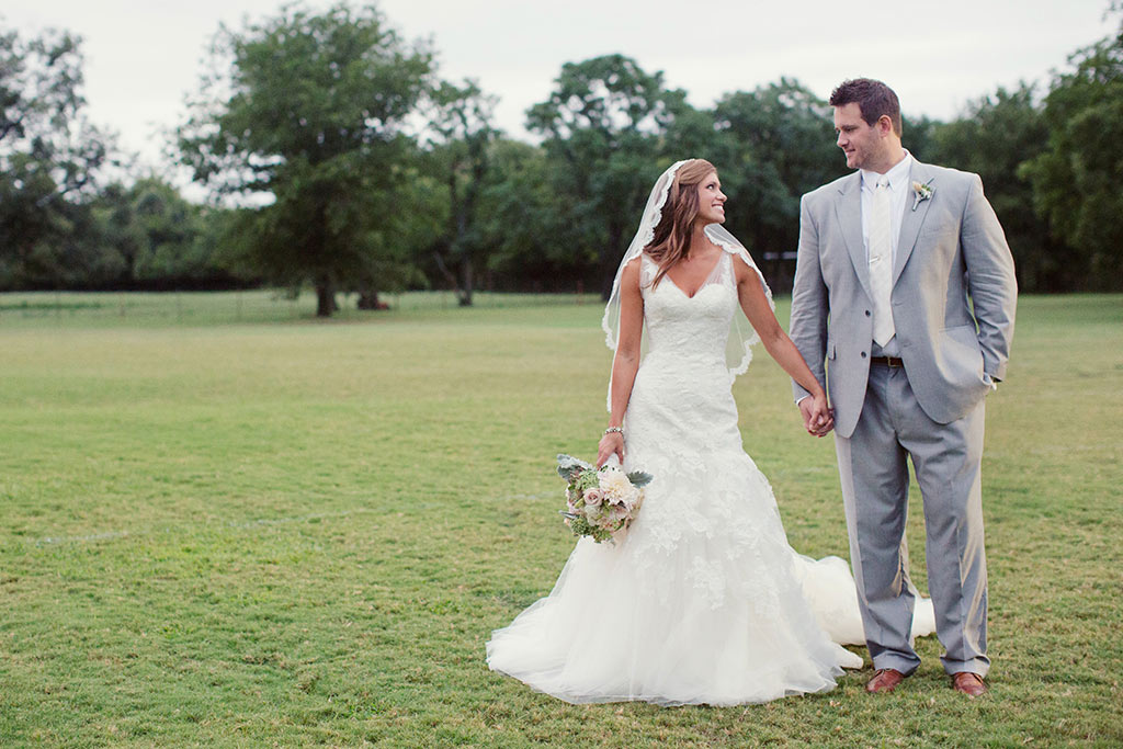 Bride and groom take a wedding day portrait in an open field at Howell Family Farms in Arlington, Texas