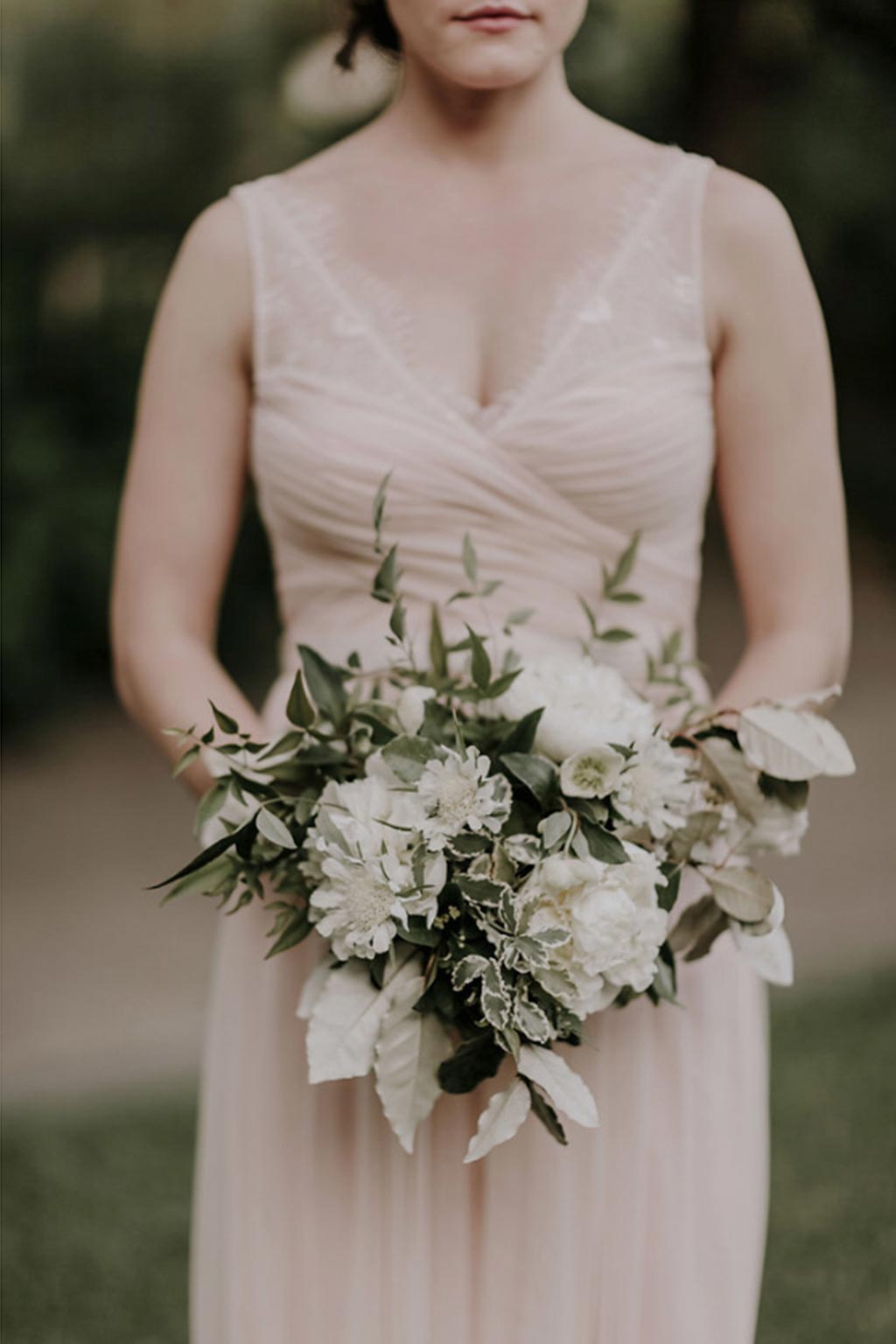 Bridesmaid with peach sleeveless gown and white and green natural bouquet