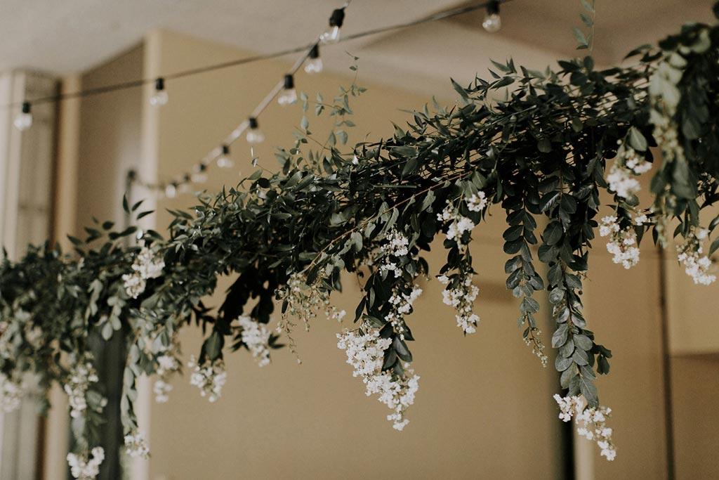Cafe lights and hanging organic greenery installation wedding detail