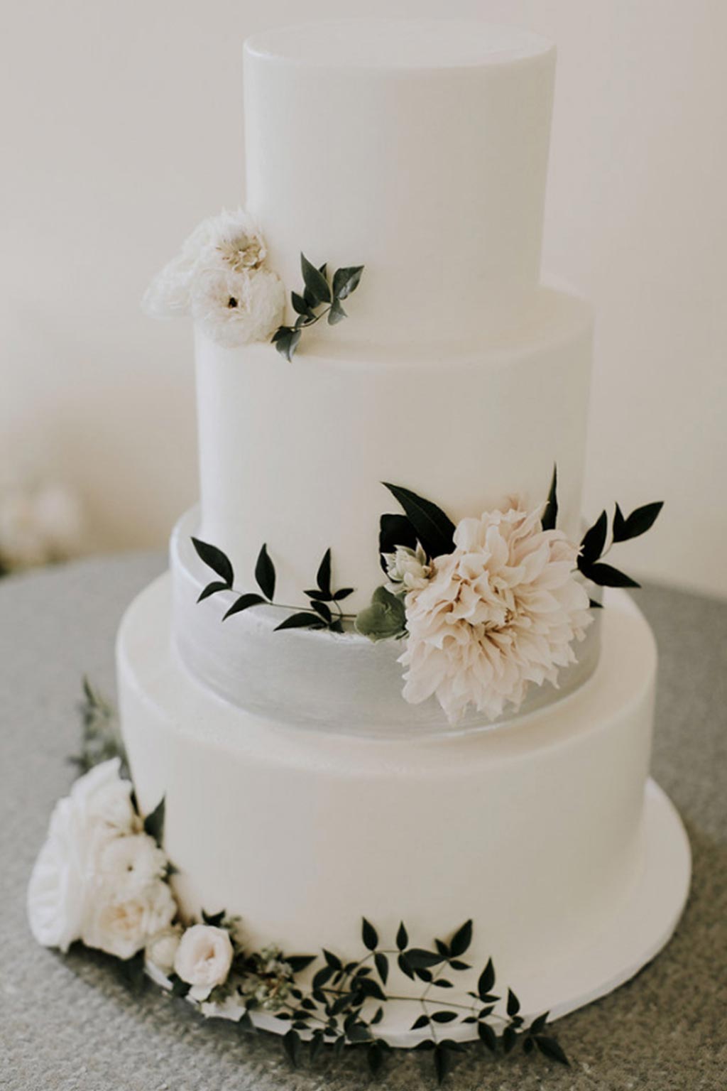 Smooth buttercream wedding cake with a silver metallic layer and frech blooms