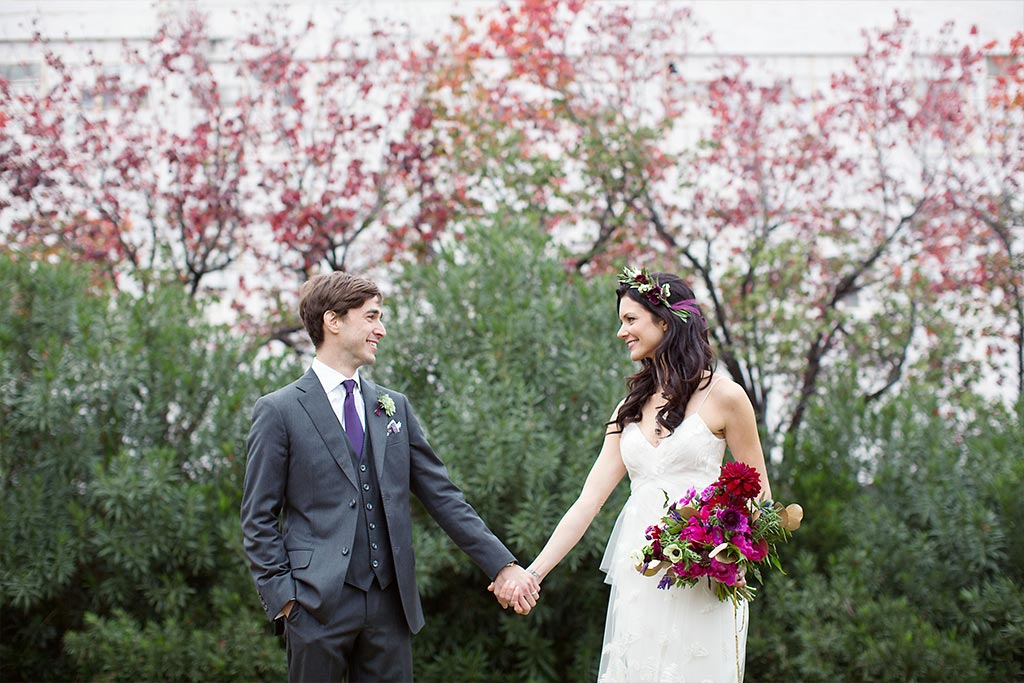 Bride and groom take a wedding day portrait in front of greenery at Hickory Street Annex in Dallas