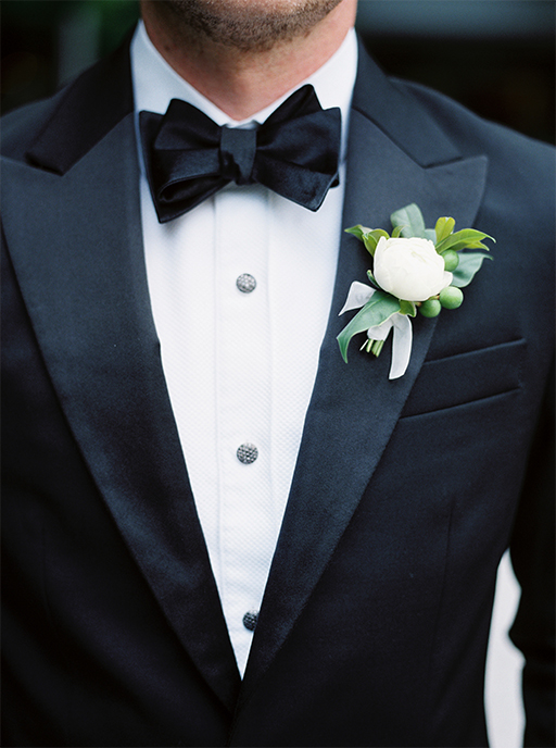 Groom’s black tux with bow tie and white boutonniere