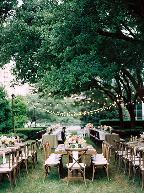 Wedding reception long table and cross back chairs with hanging cafe lights at Marie Gabrielle in Dallas